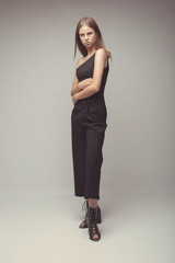 Fashionable girl in light tones in studio. Woman with unflappable face. Lifestyle concept in fashion world. Female in suit