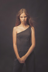 Fototapeta premium Fashionable girl in golden gray tones in studio. Woman with unflappable face. Lifestyle concept in fashion world