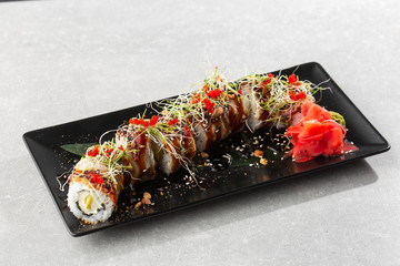 Philadelphia roll sushi with eel, avocado, cream cheese and caviar. Sushi menu. On dark stone plate in white background. Traditional japanese seafood, healthy food concept. Horizontal photo.