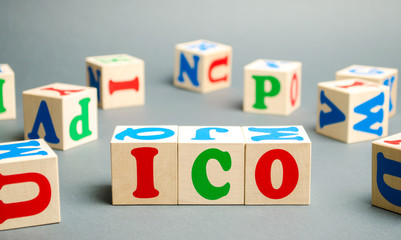 Wooden blocks with the word ICO ( Initial coin offering ) and calculator. Attracting investments in the form of selling to investors a fixed number of new units of cryptocurrencies