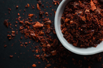 Spice red paprika in a white ceramic bowl isolated on black background