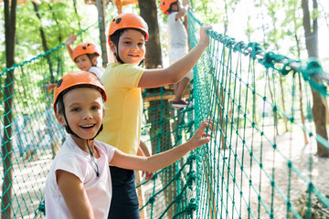 selective focus of cheerful and cute kid on high rope trail with multicultural friends