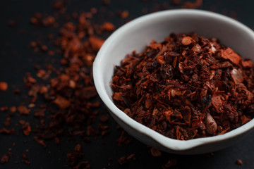 Spice red paprika in a white ceramic bowl isolated on black background