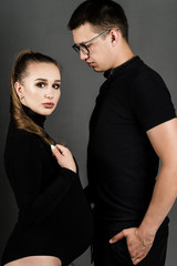 Pregnant woman with husband on a dark background. Husband and wife fashion portrait. Happy couple