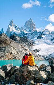 Couple in love at Mount Fitzroy. Scenic view of snowcapped mountain tops of Patagonia trek. Blue sky, turquoise lake and scenic rock landscape. Shot in Argentina. Nature, travel, adventure, hiking.