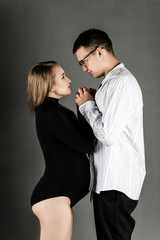 Pregnant woman with husband on a dark background. Husband and wife fashion portrait. Happy couple