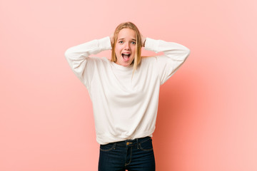 Young blonde teenager woman covering ears with hands trying not to hear too loud sound.