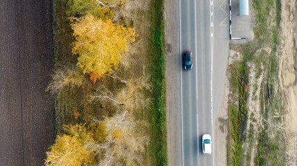 Aerial view of cars driving on country autumn road. Drone shot flying over rural road