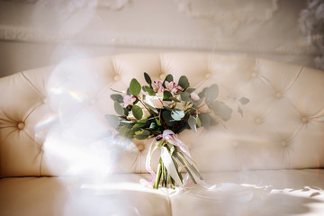 The bride holds in hands a beautiful wedding bouquet. Portrait of an elegant bride with professional makeup and hairstyle in a luxurious wedding dress. Wedding details and accessories, rustic wedding