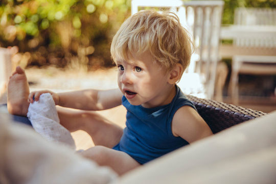 Close-up of baby boy sitting in garden chair outside