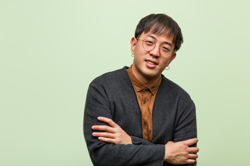 Young chinese man wearing a cool clothes style against a green background