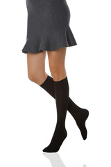 Medium bottom shot of a female figure in the gray bell-shaped skirt and black shadow-proof knee socks. The girl on tiptoe is posing on the white background. 