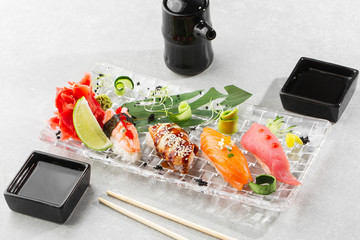 Nigiri sushi with salmon, eel, tuna and prawn, served on transparent plate. Delicious traditional Japanese food, tasty seafood, restaurant concept, food background. horizontal photo