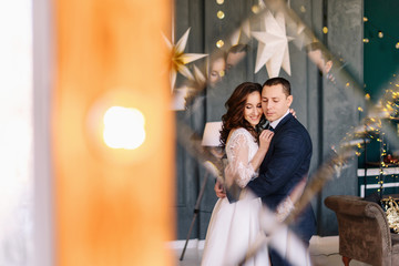 Obraz na płótnie Canvas Winter wedding. Wedding couple portrait of the bride and groom. Wedding bouquet in the hands of the bride. Photoshoot on the background of a Christmas tree with a blurred background and bokeh
