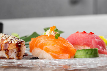 Nigiri sushi with salmon, eel, tuna and prawn, served on transparent plate. Delicious traditional Japanese food, tasty seafood, restaurant concept, food background. horizontal photo