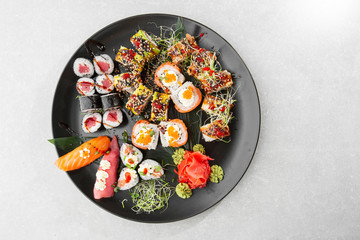 Japanese sushi set. Set of fresh tuna maki , salmon nigiri and dragon sushi rolls served on black plate close-up. Horizontal top view from above Top view flat lay. A set for a large company.