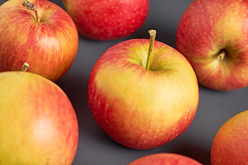 Lot of red fresh whole ripe apples full of vitamins scattered on old dark scratched concrete table on kitchen. Harvest or diet concept. Close-up