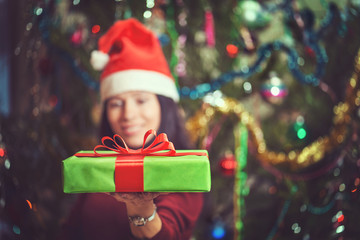 Portrait of a positive young woman opening present at Christmas time.
