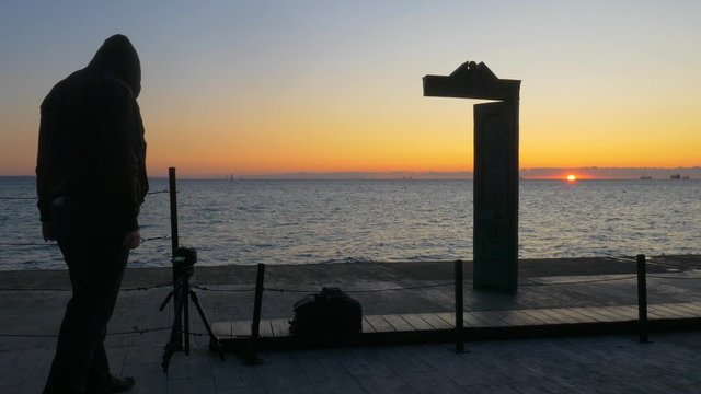 Hooded photographer takes photos of Domus Solis in Odessa at sunrise