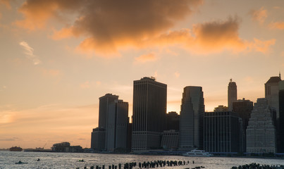 Fototapeta na wymiar Beautiful view of downtown Manhattan skyline financial district as sun goes down in tranquil sunset behind city cast orange color across evening sky