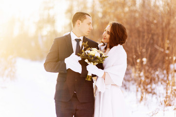Beautiful wedding couple. Winter wedding of the groom in a beautiful suit and the bride in a beautiful wedding dress. Winter photo shoot newlyweds.