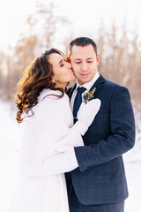 Beautiful wedding couple. Winter wedding of the groom in a beautiful suit and the bride in a beautiful wedding dress. Winter photo shoot newlyweds.