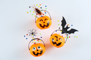 Halloween themed flat lay composition with decorative jack-o-lantern pumpkins, on paper textured background with a lot of space for text. Close up, top view.