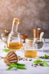 Hot tea in glass teapot and cup with steam on dark background.