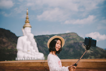Happy Asian tourist taking fun selfie at famous tourist attraction. Asia summer travel. Young woman taking mobile picture with phone at temple.