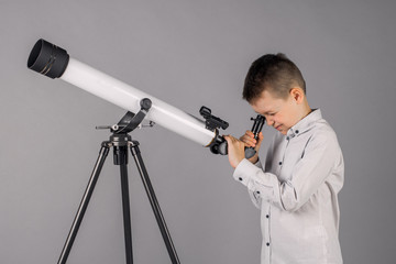 young astronomer looks through a telescope and writes in the tablet