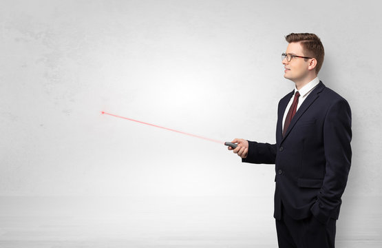 Young businessman with laser pointer and copyspace white wall