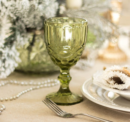 Image of Christmas dinner in home, Christmastime table setting over decorated fir tree background, glass for champagne