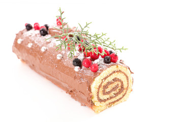 yule log, christmas pastry with chocolate and berries fruit on white background