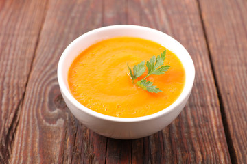 bowl of carrot soup on wood background