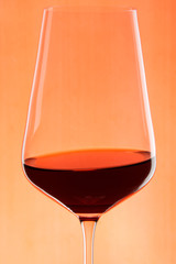 glass of red wine isolated on red background