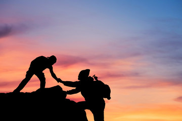 friends helping each other and with teamwork trying to reach the top of the mountains