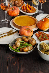 pumpkin pie, baked potatoes, pumpkins and carrots on wooden table