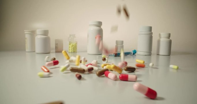 Closeup shot of different pills falling on table with tablets cans and syringes - mosern drug and pharmacy addiction, pharmaceutical industry concept 4k footage