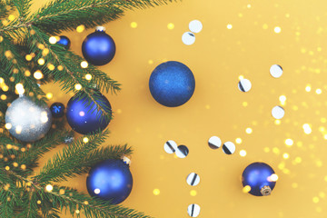 Fototapeta na wymiar Christmas tree branch decorated with blue toys on an orange background.