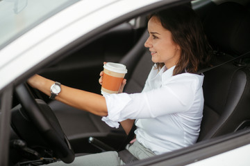 Young woman in car drinking coffee