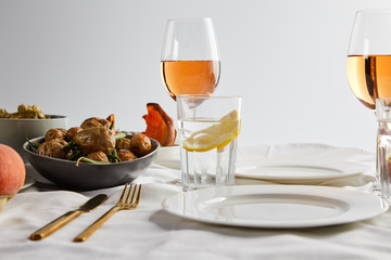 baked potatoes near glasses with rose wine and lemon water on white tablecloth isolated on grey