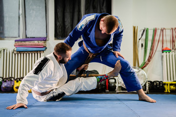 Brazilian Jiu Jitsu BJJ martial arts training sparring at the academy two fighters sit up de la...