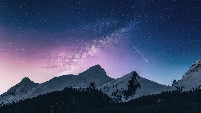 Cinemagraph of night sky moving stars over snow capped mountains