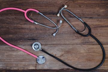 Pink and black Stethoscope on wood table.
