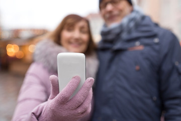 technology, winter holidays and people concept - close up of happy senior couple taking selfie by smartphone on christmas