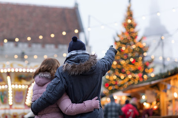 love, winter holidays and people concept - happy senior couple hugging at christmas market on town hall square in tallinn, estonia