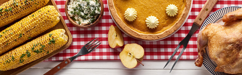 top view of pumpkin pie, turkey and vegetables served at white wooden table for Thanksgiving dinner, panoramic shot