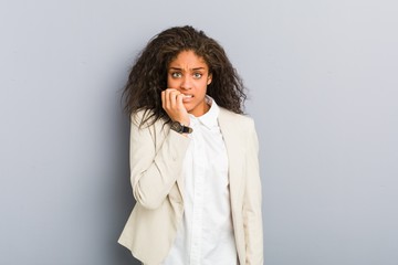 Young african american business woman biting fingernails, nervous and very anxious.