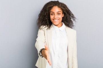 Young african american business woman stretching hand at camera in greeting gesture.