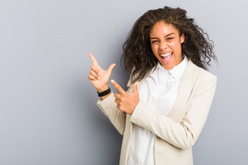 Young african american business woman pointing with forefingers to a copy space, expressing...